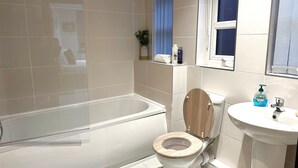 Ein modernes Badezimmer mit Badewanne, Toilette und Waschbecken.