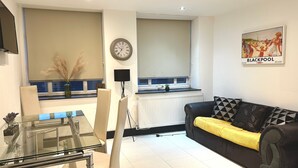 Ein modernes Wohnzimmer mit einem Glastisch, einem schwarz-gelben Sofa und einem großen Fenster mit Meerblick.