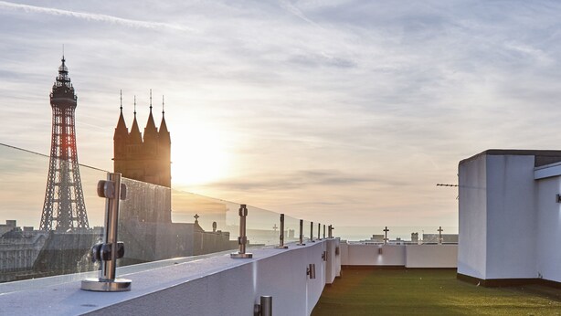 Eine Dachterrasse mit Blick auf einen Turm und eine Burg im Hintergrund.