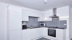Eine moderne Küche mit weißen Schränken, einer schwarzen Arbeitsplatte, einer Mikrowelle und einem Backofen.