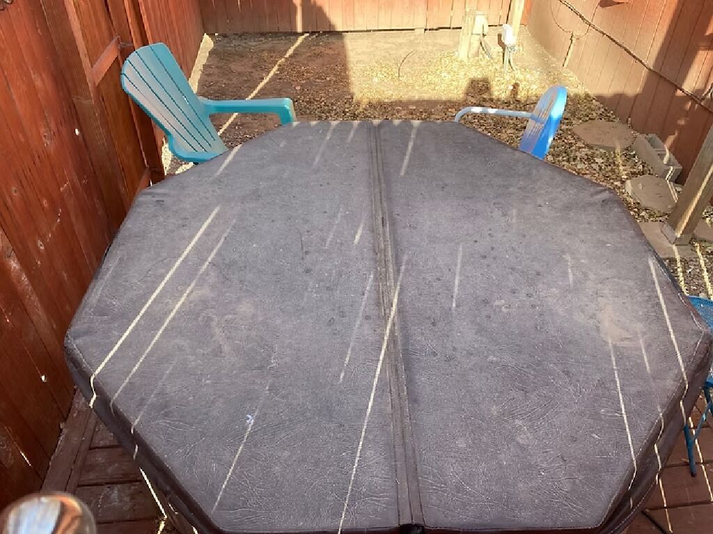 A round table with a dark surface and white lines, surrounded by blue chairs.