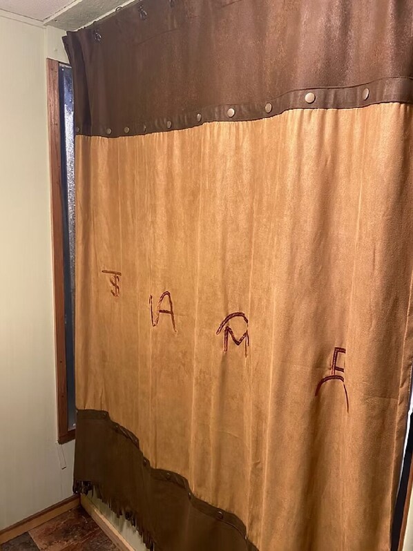 Una habitación con una cortina marrón que presenta letras bordadas que deletrean "TAM".