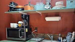 Una cocina compacta con microondas, cafetera y un refrigerador pequeño.