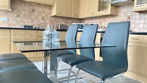 Una cocina moderna con armarios de madera, una mesa de comedor de vidrio y cuatro sillas negras.