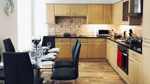 Una cocina moderna con armarios de madera, microondas, estufa y comedor con mesa dispuesta para cuatro.