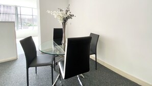 A conference room with a glass table, four black chairs, and a vase with flowers.