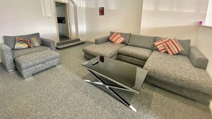 A modern living room with grey sofas, a coffee table, and a TV.