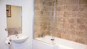 A bathroom with a sink, mirror, and shower area. - Winter Gardens Service Apartment 2 (Blackpool)
