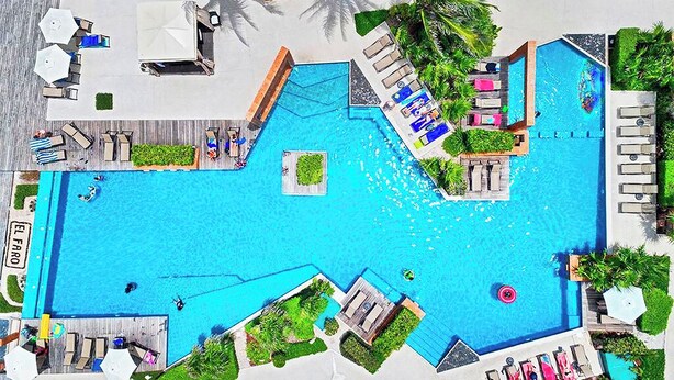 A large outdoor swimming pool with multiple lounge areas and sunbeds. - Nice Caribbean style apartment in beachfront condominium (Playa del Carmen)