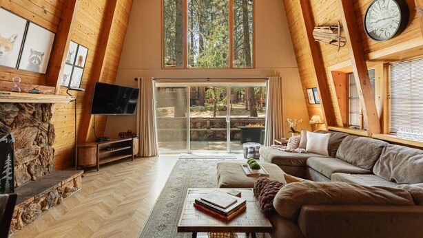 A cozy loft-style room with a fireplace, a flat-screen TV, a sofa, and a large sliding glass door leading to an outdoor area.