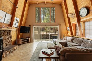 Une pièce confortable de style loft, dotée d’une cheminée, d’un téléviseur à écran plat, d’un canapé et d’une grande porte-fenêtre coulissante donnant sur un espace extérieur.