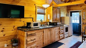 A wooden cabin interior with a kitchen featuring a wooden countertop, a microwave, and a sink. - Cabin Sweet Cabin    (laurelville)