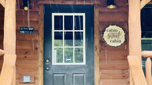 A cabin entrance with a wooden door, a welcome sign, and a 'cabin sweet cabin' sign. - Cabin Sweet Cabin    (laurelville)