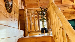 A wooden staircase with a railing, a wall-mounted decorative item, and a potted plant. - Cabin Sweet Cabin    (laurelville)