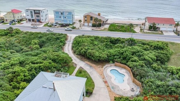 A coastal residential area with houses, a road, and a swimming pool.