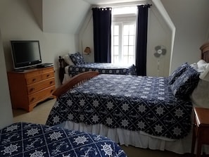 Une chambre avec deux lits, une commode, un téléviseur et une fenêtre avec des rideaux.