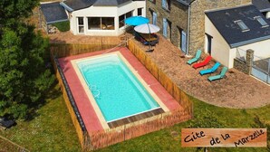 Ein Wohnhaus mit Swimmingpool, Sitzgelegenheiten im Freien und einem Steinhaus.