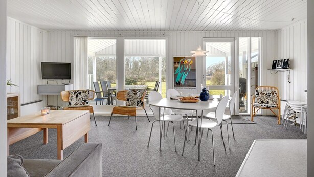 A spacious living room with a large TV, a dining area with a round table and chairs, and a cozy seating area with a sofa and chairs. - 3 bedroom nice home in Glesborg (Glesborg)