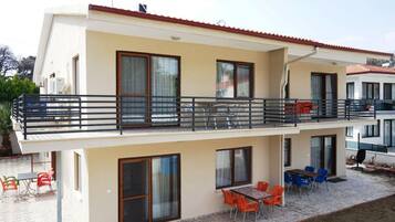 Enjoy al fresco dining on the upper floor balcony with a table and chairs, surrounded by large windows and a patio area.