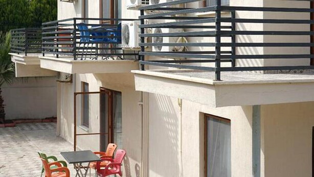 Un edificio di due piani con un balcone, posti a sedere all'aperto e condizionatori.