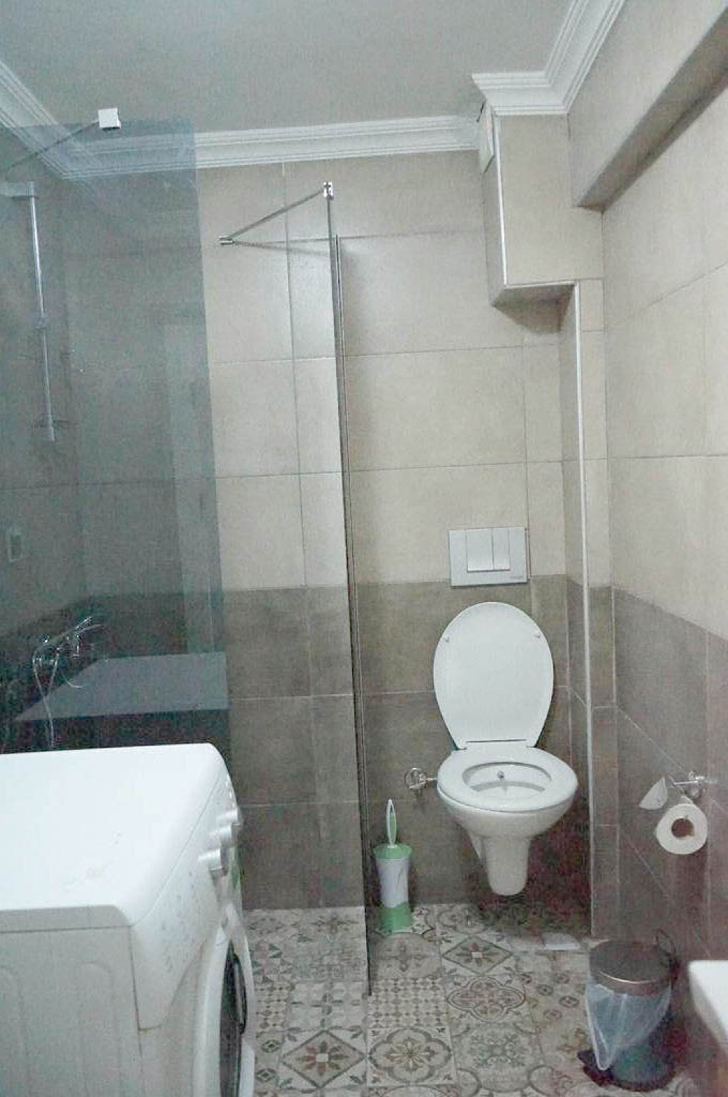 A bathroom with a shower, toilet, and washing machine.