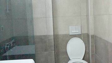 A bathroom with a shower, toilet, and washing machine.