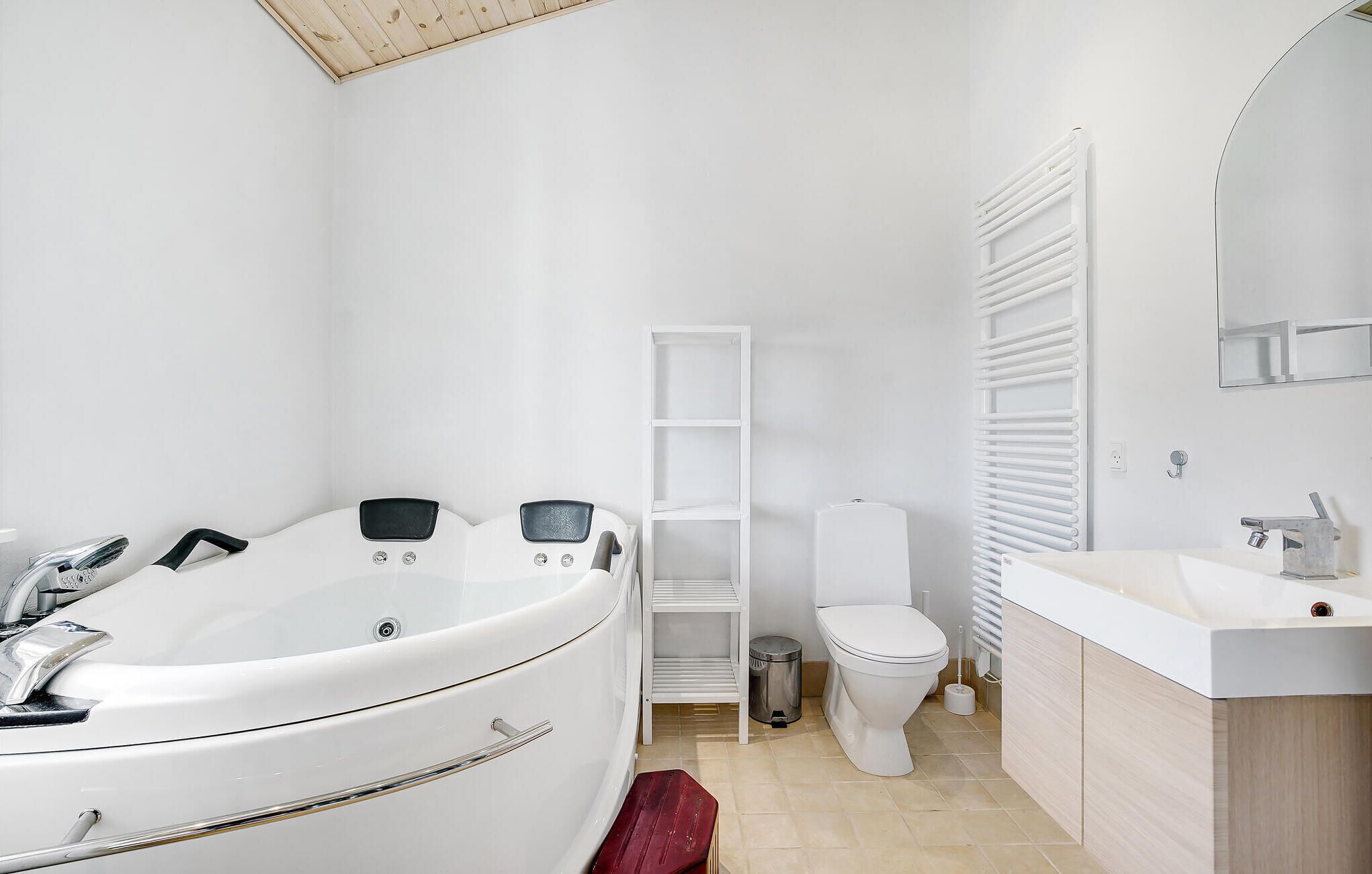 Un baño moderno con una bañera independiente, un inodoro, un lavabo y un estante empotrado.