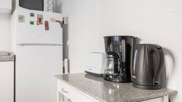 Una cocina con microondas, cafetera y hervidor eléctrico sobre una encimera de granito.
