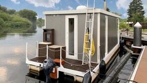 Une petite embarcation à un seul étage, dotée d’une cabine, d’un moteur hors-bord Yamaha et d’une barrière en chaîne.