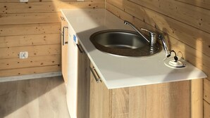 Une cuisine dotée d’un évier en acier inoxydable, de meubles en bois et d’un plan de travail blanc.