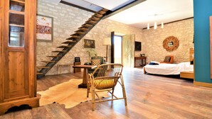 Ein Zimmer mit einer Holztreppe, einem Bett, einem Stuhl und einem Tisch.