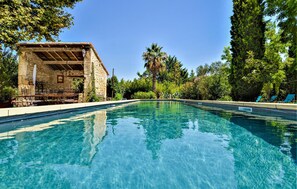 A clear swimming pool with a stone building and outdoor seating area. - Five bedroom gorgeous home in Tarascon (Tarascon)