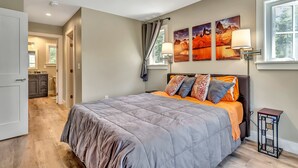 Un dormitorio con una cama, una mesita de noche, una lámpara y una ventana.