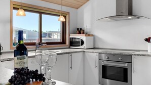 Cozinha moderna com uma janela grande, micro-ondas, forno e uma garrafa de vinho do Chile.