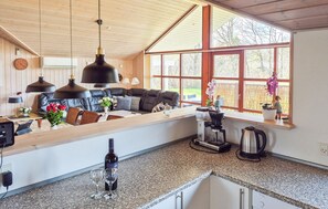 A modern kitchen with a built-in oven, a coffee maker, and a dining area with a sofa and table.