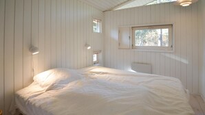 Ein Schlafzimmer mit einem großen Bett, zwei Wandleuchten, einem Fenster und einer Heizung.