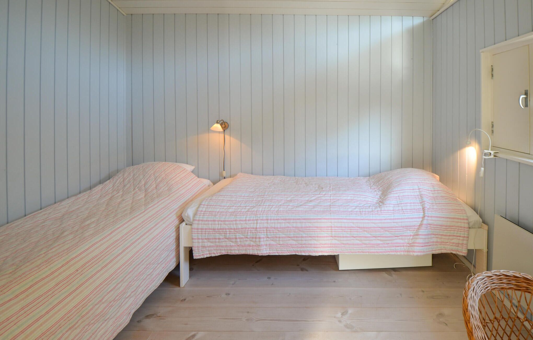 Una habitación con dos camas individuales, suelo de madera y una lámpara fijada a la pared.
