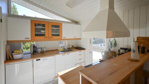 Eine moderne Küche mit weißen Schränken, Holz Arbeitsplatten und einem großen Fenster, das für natürliches Licht sorgt.