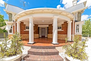 A building with a covered entrance, columns, and a brick facade.