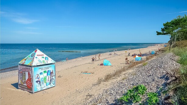 A beach with a kiosk advertising sports products, a clear sky, and calm sea. - 2 bedroom amazing home in Wicie (Wicie)