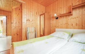 Una habitación de cabaña de madera con una cama, una silla y una mesita.