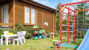 A wooden house with a play area including a slide, a climbing structure, and a table with chairs. - 2 bedroom amazing home in Wicie (Wicie)