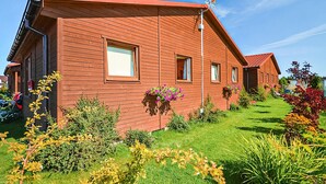 A row of red wooden cabins with small windows and a clear blue sky. - 2 bedroom amazing home in Wicie (Wicie)
