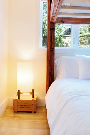Ein Schlafzimmer mit einem hölzernen Kopfteil, einem weißen Bett und einem Nachttisch aus Holz mit einer Lampe.