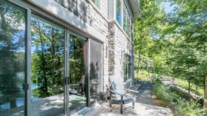A modern house with a deck, large glass doors, and a stone exterior.