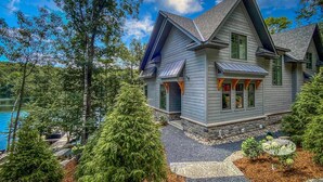 A house with a steeply pitched roof, large windows, and a stone foundation.