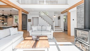 A spacious living area with a high ceiling, a staircase leading to an upper level, and a fireplace.