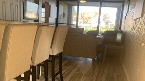 Eine moderne Küche mit Bar, Holzboden und großen Fenstern, die einen Ausblick nach draußen bieten.