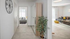 En modern inredning med en hall som leder till ett sovrum, en stor väggklocka och en krukväxt.