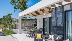 En uteplats med flätade möbler, en stenmur och en pergola.
